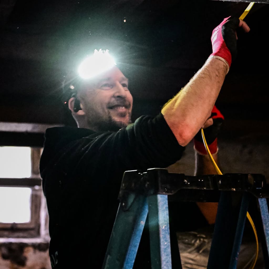 Licensed electrician wearing a headlamp while performing an emergency electrical repair on a residential electrical panel at night.
